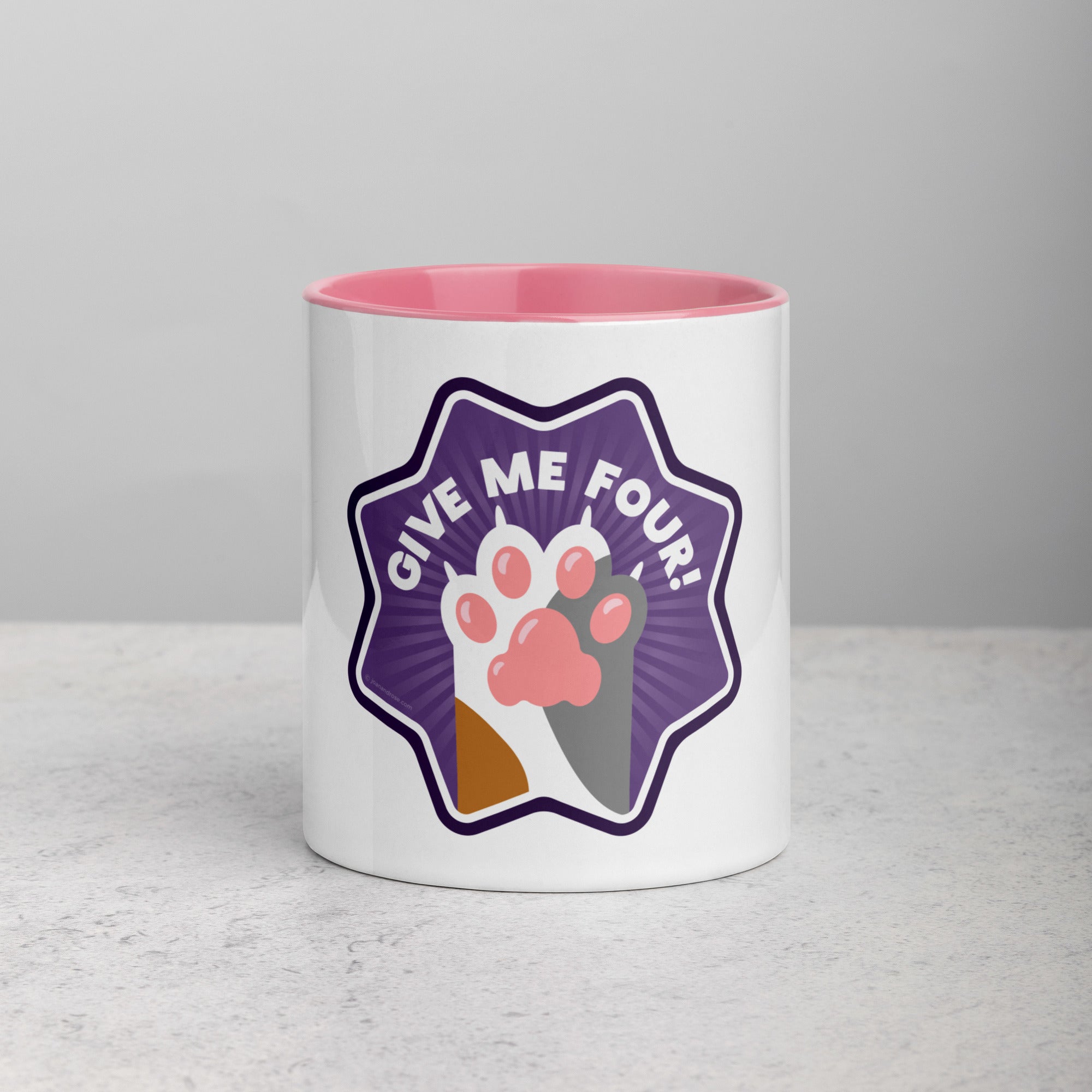 front facing image of a white mug with pink interior and handle. Mug has image of a calico cats paw on a purple 8 sided star with the text 'give me four' 